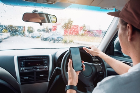 distracted driver talking on mobile phone on rainy urban street